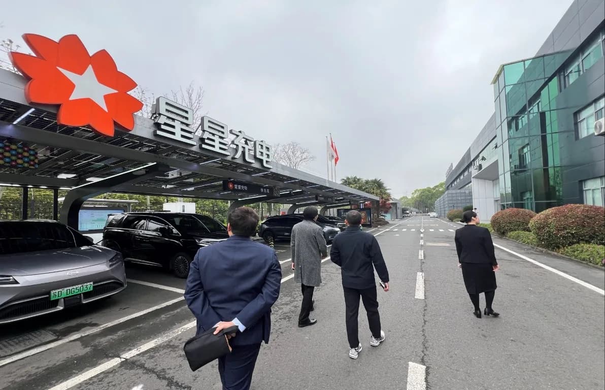 Visitors walking through the StarCharge campus under a solar canopy topped with its star logo